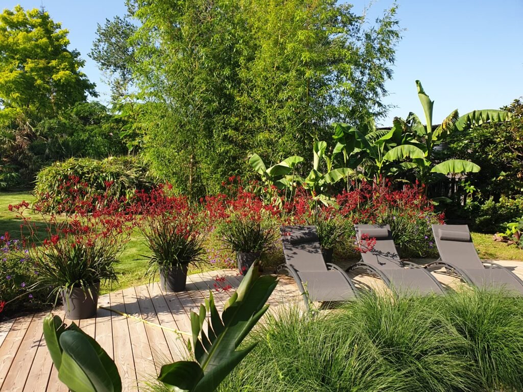 Terrasse en bois avec transats dans un jardin exotique fleuri